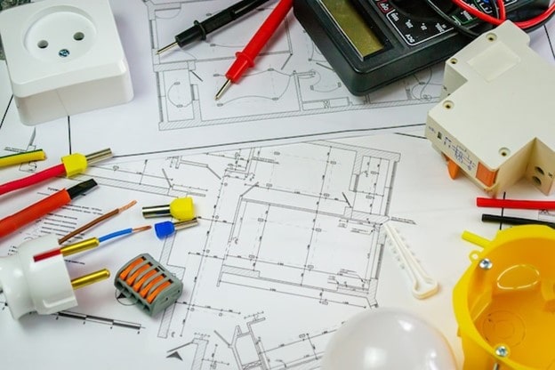 نقشه تاسیسات برقی ساختمان به همراه تجهیزات الکتریکی نظیر فیوز، سیم‌های رابط، پریز و دستگاه تست ولتاژ روی پلان کارگاهی.