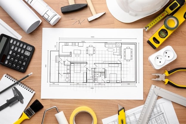 نقشه جانمایی تاسیسات ساختمان در کنار ابزارآلات فنی، متر و تجهیزات الکتریکی برای طراحی سیستم‌های مکانیکی و برقی (MEP).