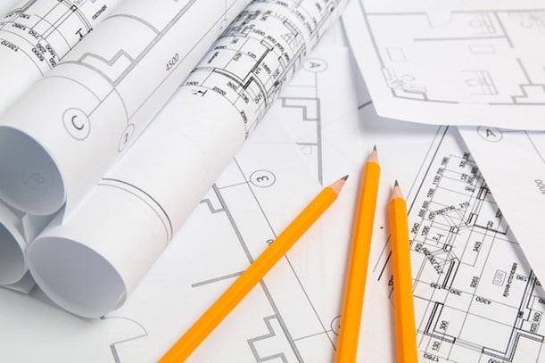 مجموعه نقشه‌های فاز ۲ ساختمانی شامل پلان‌های اجرایی، جزئیات فنی و نقشه‌های رول شده روی میز کار.